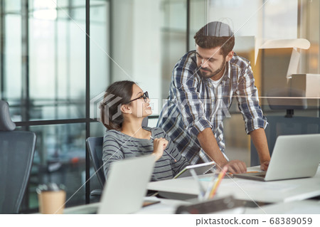 Having conversation at work. Young female and male colleagues talking and discussing project, working together in the modern coworking space 68389059