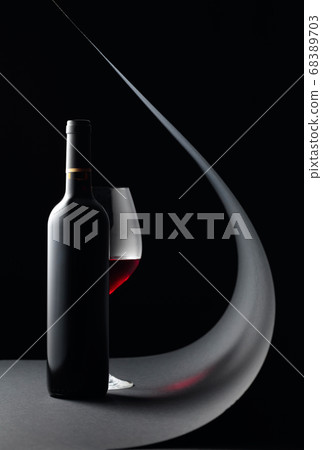 Bottle and glass of red wine on a black 68389703