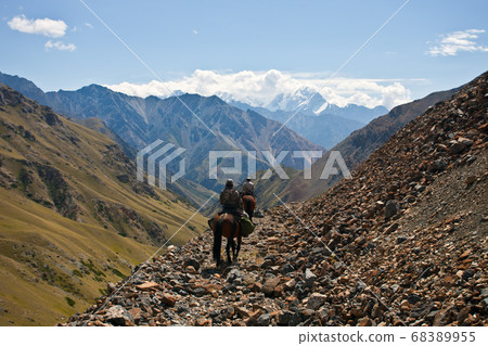 Hunters on horseback riding in the mountains  68389955