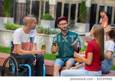 Group of friends taking a stroll on city's street in summer day Group of friends taking a stroll on city's street in summer day 68394960