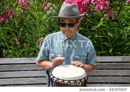 Asian man hitting djembe on a bench Vancouver Vancouver British Columbia 68397607