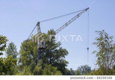 Old abandoned rusty tower crane on the background of trees and blue sky. 68398166