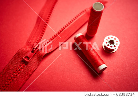 threads and zipper on a red minimalistic background 68398734