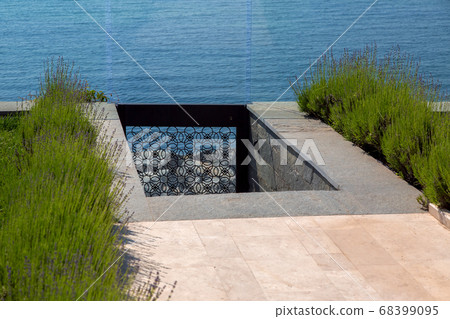 descent to the sea from the backyard with a walkway of marble tiles and a stone staircase with lavender and blue sea through a wrought iron gate and a glass fence. descent to the sea from the backyard with a walkway of marble tiles and a stone staircase with lavender and blue sea through a wrought iron gate and a glass fence. 68399095
