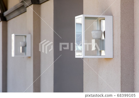 square hinged lantern on the wall in an iron case with a glass and a white lamp. 68399105