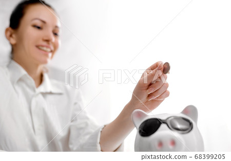 Happy woman tops up her savings in pig piggy bank 68399205
