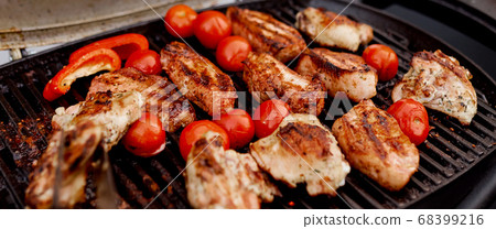 juicy roasted meat, tomatoes, red pepper on the grill on the street 68399216