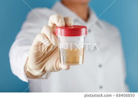 A doctor in a white coat holds a plastic container 68408850