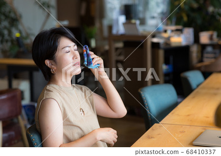 Woman in her 40s wiping her sweat off with a handkerchief 68410337