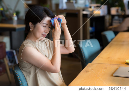 Woman in her 40s wiping her sweat off with a handkerchief Woman in her 40s wiping her sweat off with a handkerchief 68410344
