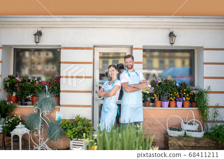 Bearded male and brown-haired female standing back to back with crossed arms, smiling Bearded male and brown-haired female standing back to back with crossed arms, smiling 68411211