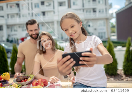 Pretty girl in white tshirt making selfie with parents Pretty girl in white tshirt making selfie with parents 68411499