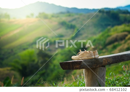 The white shoes traces the journey on a natural wooden chair in the middle of the mountain, the mist clouds, the beautiful sky and the warm light give a sense of the story. 68412102