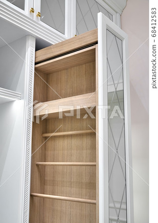 White wardrobe with mirror doors. Vertical pull-out wooden cabinet in the dressing room. Classic furniture White wardrobe with mirror doors. Vertical pull-out wooden cabinet in the dressing room. Classic furniture 68412583