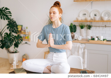 Portrait of peaceful meditating redhead young woman is putting her hands together Portrait of peaceful meditating redhead young woman is putting her hands together 68414497