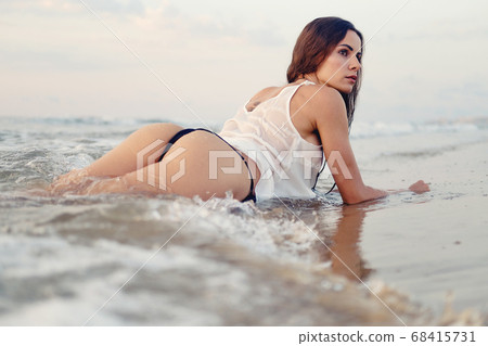 Sexy woman posing on beach near the sea at sunrise 68415731