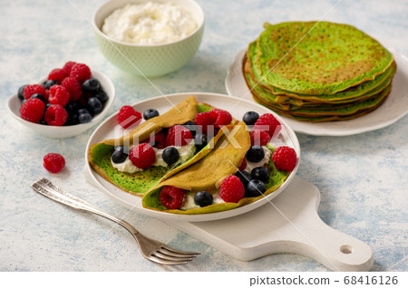 Spinach crepes with cheese , raspberries and blueberries. Spinach crepes with cheese , raspberries and blueberries. 68416126