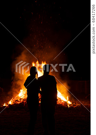 Silhouette of a couple in front of a giant bonfire 68417266