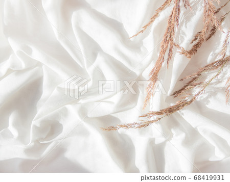 Top view on dried grass. Flat lay still life concept. Decorative autumn plants on crumpled white fabric. Cozy home background with copy space. Handmade natural decorations. Sunlight and shadow. 68419931