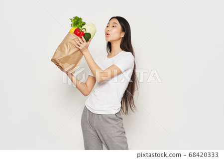 Slender woman in sportswear holds in her hand a packet with vegetables calorie Slender woman in sportswear holds in her hand a packet with vegetables calorie 68420333