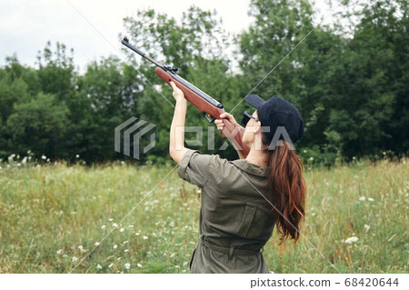 Military woman holding gun up sight hunting back view fresh air green  68420644