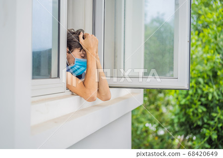 Extremly tired young man looking out the window, home alone. self-isolation at home, quarantine due to pandemic COVID 19. Mental health problems in self-isolation at home 68420649