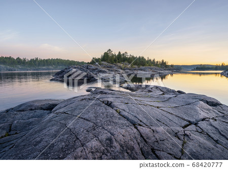 Beautiful sunrise on a rocky shore. Mixed forest 68420777