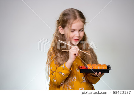 Little girl licks sushi sticks and keeps box rolls 68423187