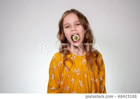 Girl puts roll in his mouth and looking at camera. Girl puts roll in his mouth and looking at camera. 68423188