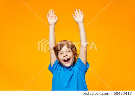 Red-haired boy with his hands up on a yellow background Red-haired boy with his hands up on a yellow background 68423417