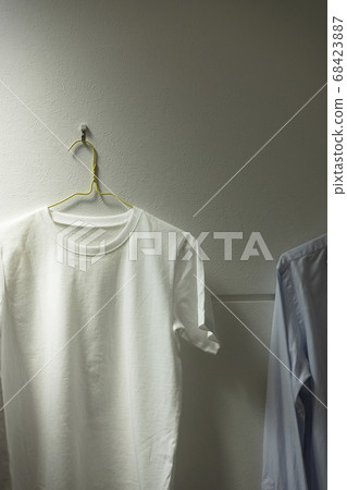 One white t-shirt hung in the room. Room, living room, room drying, laundry, etc. 68423887