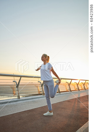 Sporty Caucasian woman stretching her leg muscles Sporty Caucasian woman stretching her leg muscles 68423986