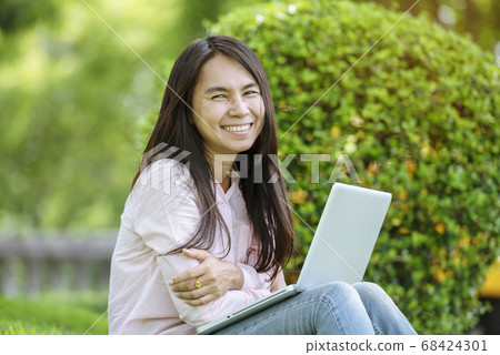 Asian woman sitting green park using laptop 68424301