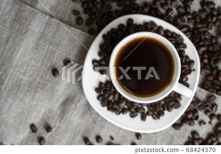 Coffee cup with roasted coffee beans on linen background. Mug of black coffe with scattered coffee beans. Fresh coffee beans. Coffee cup with roasted coffee beans on linen background. Mug of black coffe with scattered coffee beans. Fresh coffee beans. 68424370
