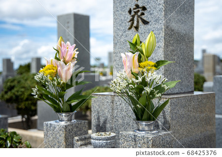 A grave with pink, yellow and white flowers 68425376