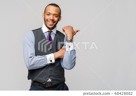 Happy african-american businessman showing his thumb up with smile over grey background Happy african-american businessman showing his thumb up with smile over grey background 68428082