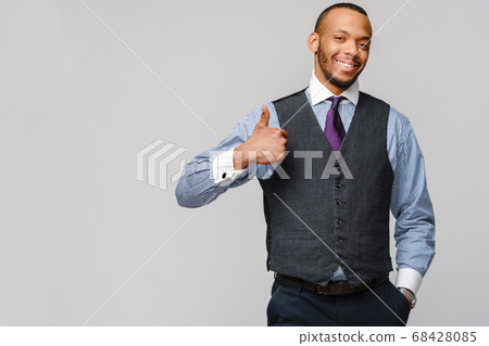 Happy african-american businessman showing his thumb up with smile over grey background Happy african-american businessman showing his thumb up with smile over grey background 68428085