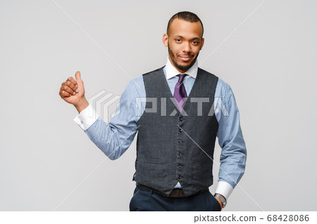 Happy african-american businessman showing his thumb up with smile over grey background Happy african-american businessman showing his thumb up with smile over grey background 68428086