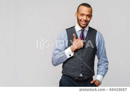 Happy african-american businessman showing his thumb up with smile over grey background 68428087