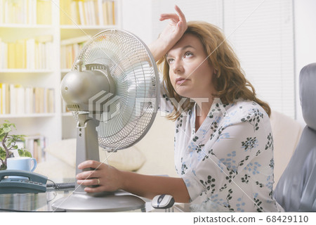 Woman suffers from heat in the office or at home 68429110