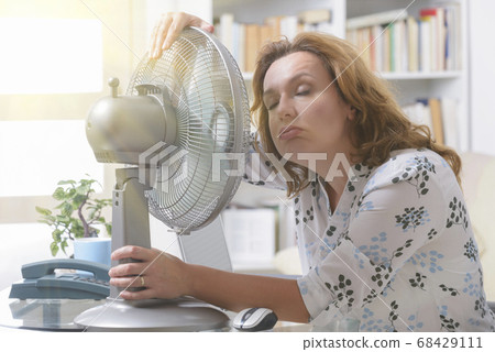 Woman suffers from heat in the office or at home 68429111