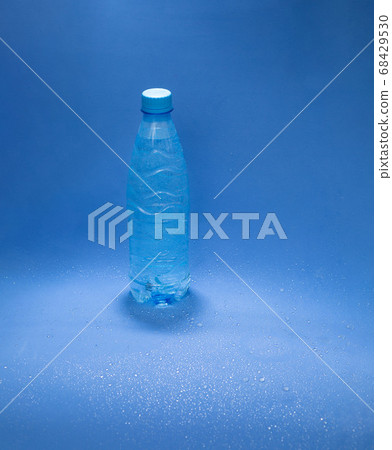 Blue plastic water bottle on a blue background with water drops 68429530