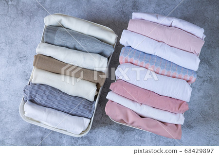 Neatly folded clothes in open organizer boxes top view on stone table. Marie Kondo tidyng method Neatly folded clothes in open organizer boxes top view on stone table. Marie Kondo tidyng method 68429897