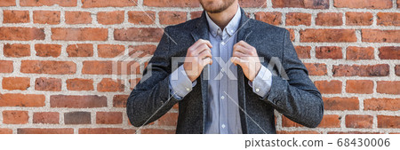 Suit man young businessman adjusting his blue coat smart casual outfit against brick wall background banner panorama at office. Urban lifestyle 68430006
