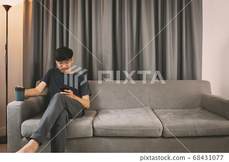 Young man sit down on the sofa while using mobile 68431077