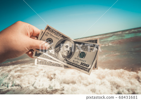 Girl holding a money bill of 300 dollars on background of sea waves Girl holding a money bill of 300 dollars on background of sea waves 68431681