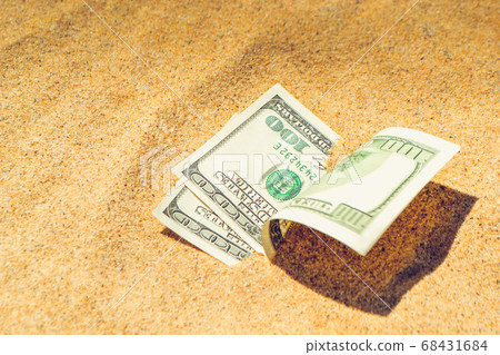 Money dolars half covered with sand lie on beach close-up 68431684