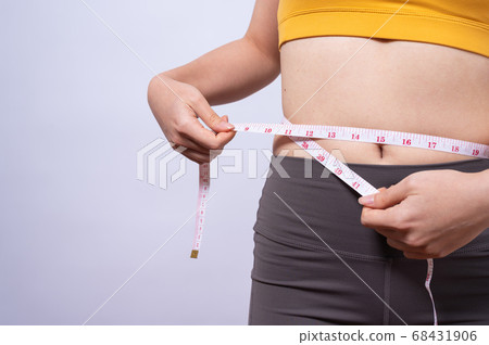 Asian sporty woman measuring her waist by measure tape isolated on white backgroun 68431906