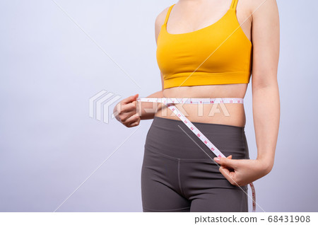 Asian sporty woman measuring her waist by measure tape isolated on white backgroun Asian sporty woman measuring her waist by measure tape isolated on white backgroun 68431908