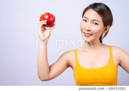 A sporty Asian woman in sportswear holding an apple isolated on white background 68432092